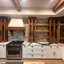 Custom kitchen with white cabinetry, wood beams, and stone backsplash built by Elite Solutions of Texas